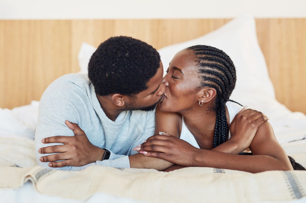 Young couple sharing an intimate kiss in the morning in bed at home